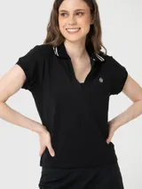 Remera de manga corta con cuello polo y abertura frontal en V. Presenta detalles de rayas blancas en el cuello y un pequeño logo bordado en el pecho.