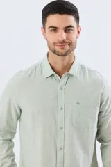 Camisa de lino de manga larga en color beige, con cuello camisero, cierre frontal de botones y un bolsillo ojal en el pecho.