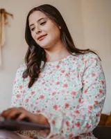 Pijama de dos piezas, compuesto por una remera de manga larga con estampado floral y un pantalón liso color rosa.