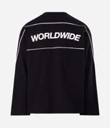 Remera de manga larga Blue Steel, color negro, con diseño de cuello redondo y corte relajado. Presenta un estampado frontal con la palabra 'WORLDWIDE' en letras blancas y detalles de líneas horizontales en contraste.