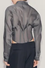 Corset tipo bomber de la colección Zara Woman, confeccionado en hilatura con mezcla de viscosa transparente, con cuello subido, manga larga y varillas interiores que definen la estructura. Cuenta con cierre frontal mediante ganchos metálicos.