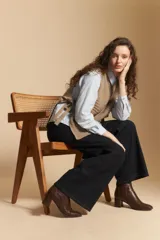 Chaleco de tejido de punto en color crema, con cuello alto y diseño acanalado. Presenta una silueta relajada con aberturas laterales.