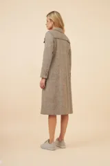 Tapado largo de corte recto confeccionado en lana fina sin teñir. Presenta cuello solapa, cierre frontal con botones, bolsillos laterales con tapa y detalles aplicados en la parte delantera. Incluye forro interior y tajo en la espalda.