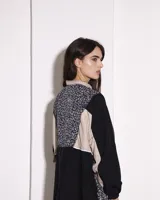 Buzo de estilo deportivo con diseño de paneles en colores negro y beige, destacando un panel central en la espalda con estampado animal print. Presenta mangas largas con puños elásticos y cuello alto.