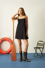 Vestido corto negro con tirantes finos y escote cuadrado. Toda la superficie del vestido está cubierta con pequeñas aplicaciones de pedrería.