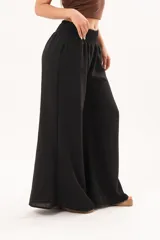 Pantalón palazzo negro de corte ancho, con cintura elástica fruncida y diseño fluido.