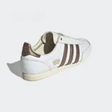 Championes Adidas modelo Japan confeccionados en cuero blanco con detalles metálicos en color bronce en las tres tiras laterales y el talón. Poseen un diseño de perfil bajo inspirado en los años 60, con puntera reforzada de doble costura, cierre de cordones y suela de caucho delgada.