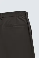 Pantalón de corte regular fit, color negro, confeccionado en tejido elástico. Presenta cintura elástica, cierre frontal con cremallera y botón, bolsillos laterales y bolsillos traseros de vivo.