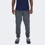 Pantalón jogger deportivo New Balance, color gris oscuro, confeccionado en tejido de poliéster reciclado con tecnología NB DRY. Presenta cintura elástica con cordón de ajuste interno, dos bolsillos laterales y puños elásticos en los tobillos.