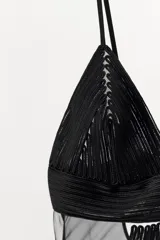 Body negro semitransparente con escote en V y tirantes finos ajustables. Combina paneles de malla con tejido de textura lineal a tono. Posee cierre en la parte inferior con botones a presión y en la espalda con ganchos metálicos.