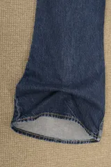 Jeans de denim azul oscuro con lavado vintage, tiro alto y corte acampanado.