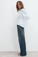Jeans de tiro medio con corte relajado y diseño de cinco bolsillos. Presenta trabillas en la cintura, cierre frontal con cremallera y botón metálico, con un acabado de lavado desgastado.