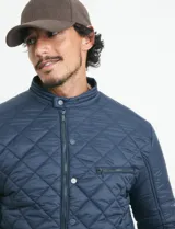 Campera capitoneada de color azul, con cierre frontal de metal y botones a presión. Presenta bolsillos con cierre de metal en el pecho y laterales, y cuello tipo mao.