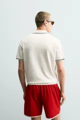 Polo de punto tejido en algodón, de corte regular fit. Presenta cuello solapa con cierre frontal de botones y manga corta, con acabados en rib y detalles de bandas a contraste en cuello y puños.