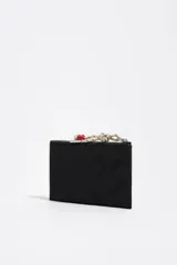 Billetera Bimba Y Lola de color negro, con cierre superior de cremallera, bolsillo frontal con cremallera y tirador decorativo de cordón claro con detalles rojos y plateados. Cuenta con el logo impreso en la parte frontal.