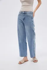 Pantalón de jean azul de corte recto y tiro medio, con detalles de estrellas bordadas a lo largo de los laterales externos de las piernas.