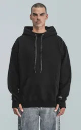 Hoodie negro de calce regular confeccionado en frisa gamuzada de algodón. Presenta capucha forrada con cordón regulable, bolsillo tipo canguro al frente y puños con abertura para el dedo pulgar.