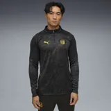 Buzo deportivo Puma del Club Atlético Peñarol, modelo de entrenamiento con cierre frontal de 1/4. Presenta un diseño en tonos negros con estampado sutil, logo de la marca y escudo del club en amarillo.