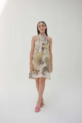 Vestido corto con estampado floral en tonos beige, verde y marrón, con cuello halter y lazo.