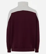 Buzo deportivo de corte oversized, con diseño bicolor en bordó y blanco. Presenta cuello alto con cierre de botones a presión, mangas largas con textura acanalada y puños elásticos.