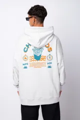 Buzo canguro oversize de algodón rústico, color gris claro, con capucha y cordones ajustables con logo estampado. Presenta un diseño gráfico pequeño en el pecho y detalles estampados en la manga.
