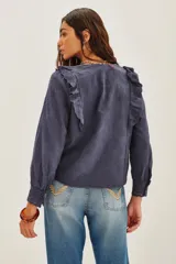 Camisa de algodón azul marino con diseño texturizado, cuello mao y volados frontales. Presenta mangas largas con puños ajustados y detalles de encaje en los bordes.
