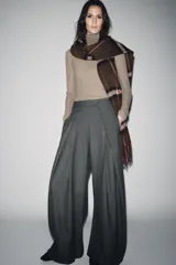 Pantalón de tiro medio con corte wide leg, confeccionado en tejido con viscosa y diseño de raya diplomática. Presenta pinzas frontales, bolsillos laterales ocultos y cierre frontal con cremallera, botón y ganchos metálicos.