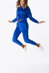 Conjunto deportivo de terciopelo azul eléctrico, compuesto por un buzo de corte holgado con cuello redondo y puños ajustados, y un pantalón jogger con cintura elástica y bolsillos laterales.