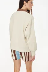 Sweater de punto color amarillo con diseño relajado y escote redondo, confeccionado en mezcla de algodón y acrílico. Presenta un bordado frontal con motivo de sol y reflejos acompañado de la inscripción "Petra".