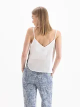 Top blanco de tirantes finos con escote en V y diseño fluido.