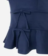 Blusa de punto roma color azul marino, con diseño estructurado, manga corta, recortes que definen la silueta, detalles de lazos decorativos en el frente y ruedo con volado peplum.