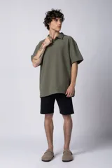 Chomba de manga corta con cuello polo, confeccionada en tejido de punto acanalado de textura pesada. Presenta un calce relajado y cuenta con una pequeña etiqueta distintiva en el ruedo.