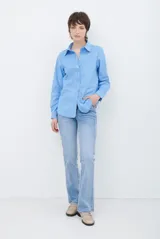 Camisa de estilo casual confeccionada en material tipo gamuza color marrón, con cuello clásico, cierre frontal con botones y costuras a la vista en tono contrastante.