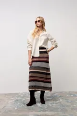 Falda midi de tejido de punto con diseño de rayas horizontales en tonos tierra, marrón, negro y beige. Presenta un corte recto y tiro alto.