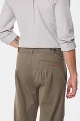 Pantalón de vestir color verde oliva, de corte recto, con bolsillos laterales y traseros. Se ajusta a la cintura con cinturón de cuero marrón.