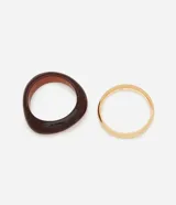 Kit de dos pulseras rígidas: una de resina marmolada color ámbar con forma orgánica y otra de metal dorado con baño light gold.