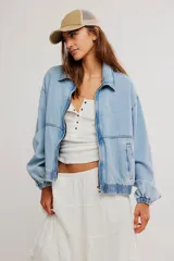 Campera bomber oversize de denim suave, color azul claro con efecto gastado, cierre frontal metálico y elástico en puños y cintura.