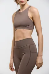 Top deportivo de compresión media con escote redondo, diseño al cuerpo y espalda abierta. Cuenta con elástico interno en la cintura para mayor sujeción.