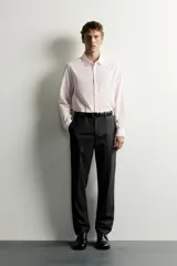 Camisa de corte regular fit color rosado pálido, con cuello solapa, manga larga y cierre frontal de botones.