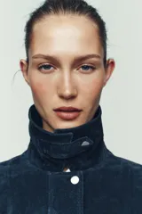 Cazadora estilo bomber confeccionada en piel, con cuello solapa, manga larga y cierre frontal con cremallera oculta y botones a presión. Presenta bolsillos delanteros de plastrón con solapa y botón a presión.