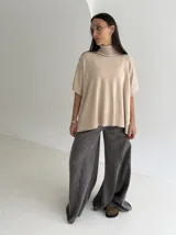 Poncho de tejido de punto color marrón chocolate, con cuello alto tipo polera y mangas cortas amplias. Presenta un diseño holgado con terminaciones acanaladas en el ruedo.