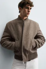 Cazadora bomber marrón con interior efecto pelo, cuello y puños de rib elástico, bolsillos de vivo en cadera, bolsillo interior y cierre frontal con cremallera.