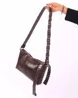 Bandolera de cuero negro con diseño rectangular, caracterizada por una correa ancha decorada con múltiples ojales metálicos y detalles de costuras laterales entrelazadas.