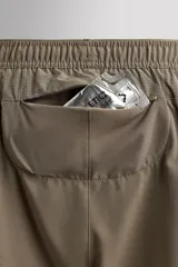 Short deportivo de entrenamiento en tejido técnico ligero y elástico, con cintura elástica ajustable mediante cordón. Presenta bolsillos frontales, un bolsillo trasero con cierre y aberturas laterales en el bajo. Incluye un pequeño logo estampado en la pernera.