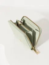 Billetera pequeña color bordó de cuero vacuno graneado con cierre de cremallera y logo de marca gofrado en el frente.