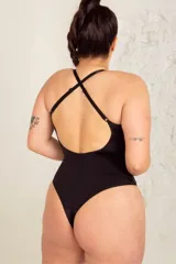 Body colaless negro de LYCRA® con breteles elásticos regulables cruzados en la espalda y detalle de aros metálicos en el frente. Tiene broche en la entrepierna con fundillo de algodón 100%.