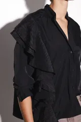 Camisa negra de nylon con cuello mao y volados de poliéster en el hombro.
