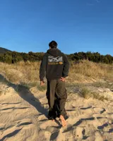 Hoodie de corte regular en color gris melange, con capucha, mangas largas y bolsillos tipo canguro. Presenta un estampado gráfico en la espalda con la inscripción 'Fletes' y una ilustración de una grúa transportando una planta.