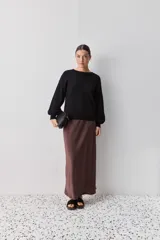 Sweater negro de tejido suave con escote redondo, mangas largas y calce relajado, con terminaciones acanaladas en cuello, puños y ruedo.
