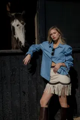 Minifalda color crema de cuero ovino con flecos y detalles en cuero marrón. Cierre frontal con cremallera. Estilo country.